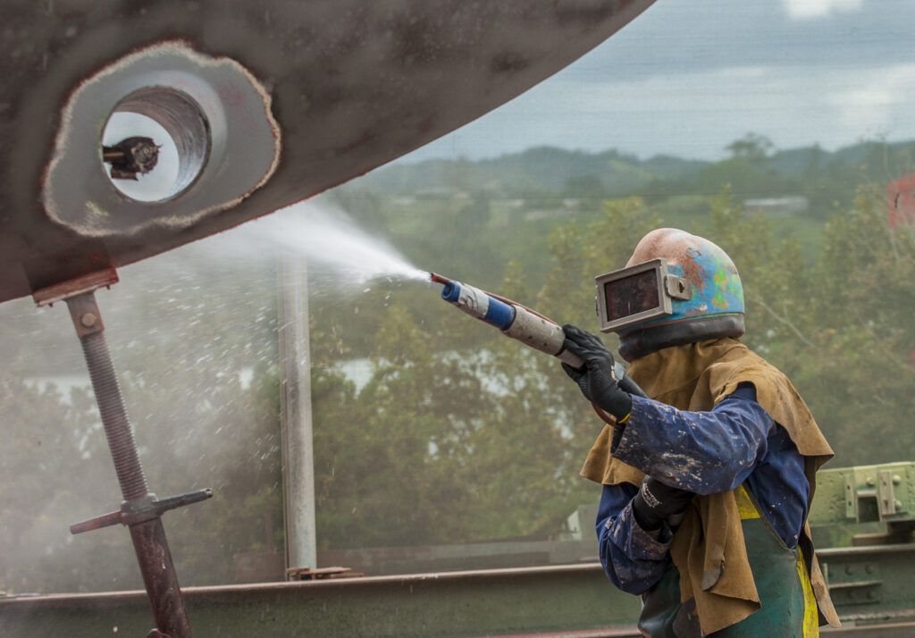 worker sandblasting the corroded hull of a boat 2023 08 21 23 33 24 utc 1