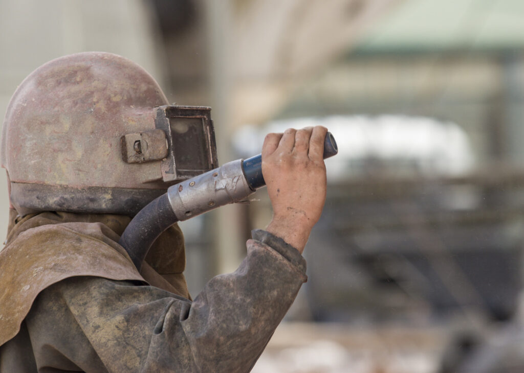 worker sandblasting the corroded hull of a boat 2023 08 21 23 33 29 utc 1